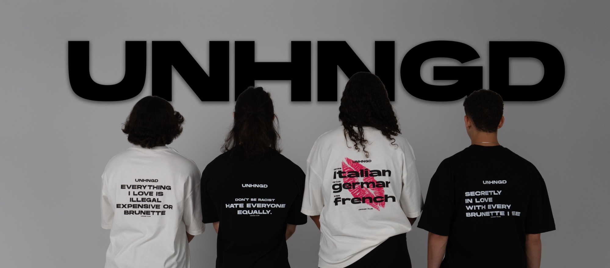 The UNHNGD Drop 01 campaign — four tees photographed from behind against the UNHNGD wall